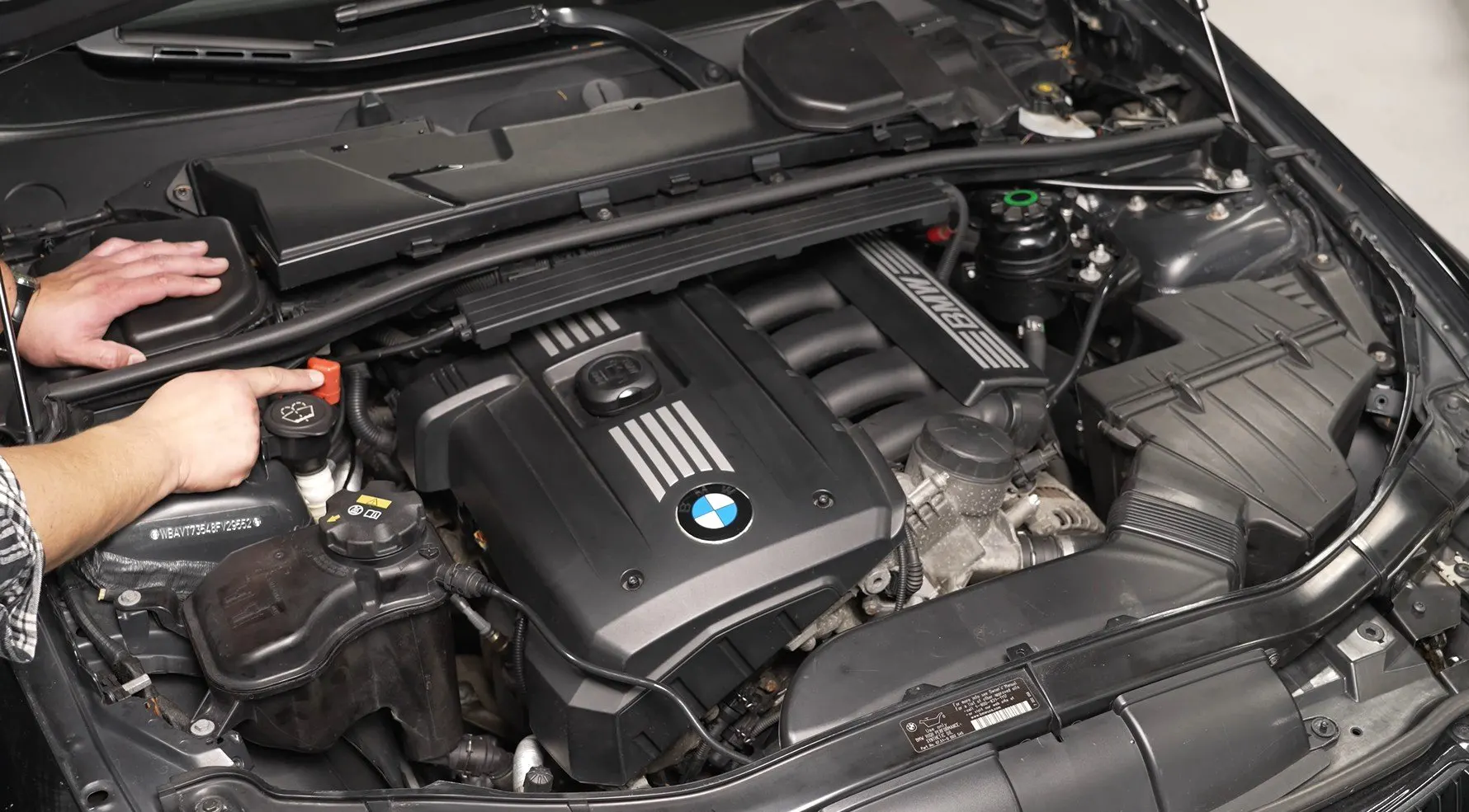 Technician working in the engine bay of a BMW during an engine repair in Clayton